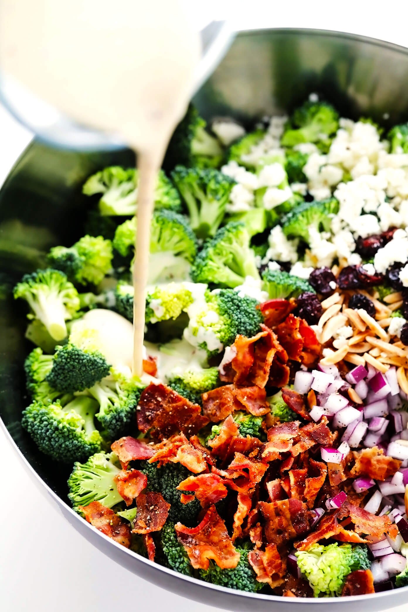 Pouring creamy dressing into broccoli salad