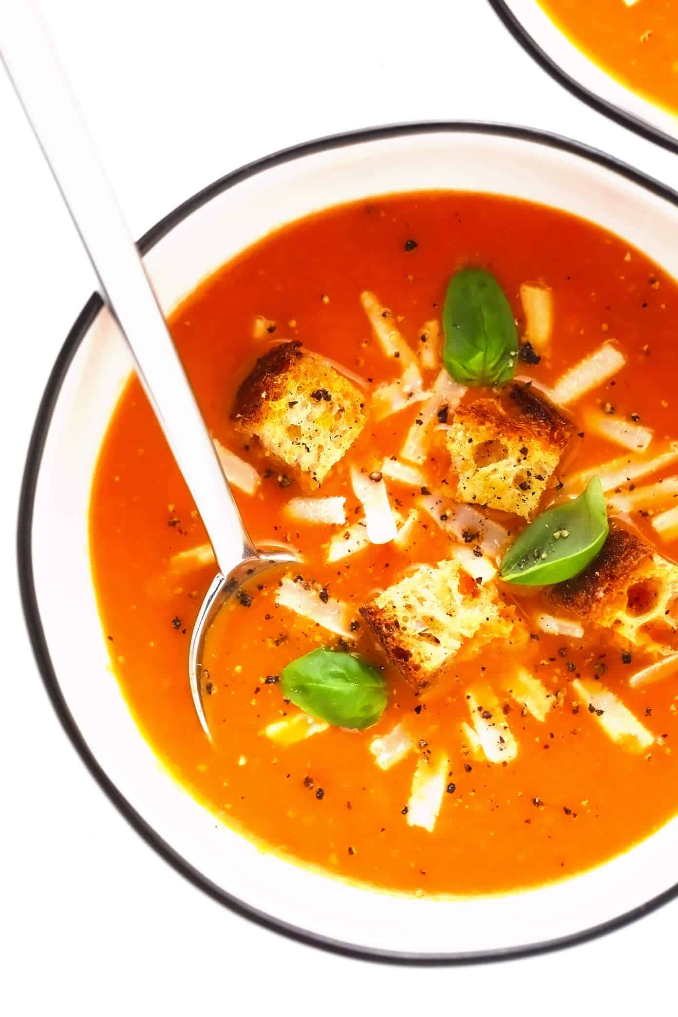 Roasted tomato soup in bowls with Parmesan, croutons and basil