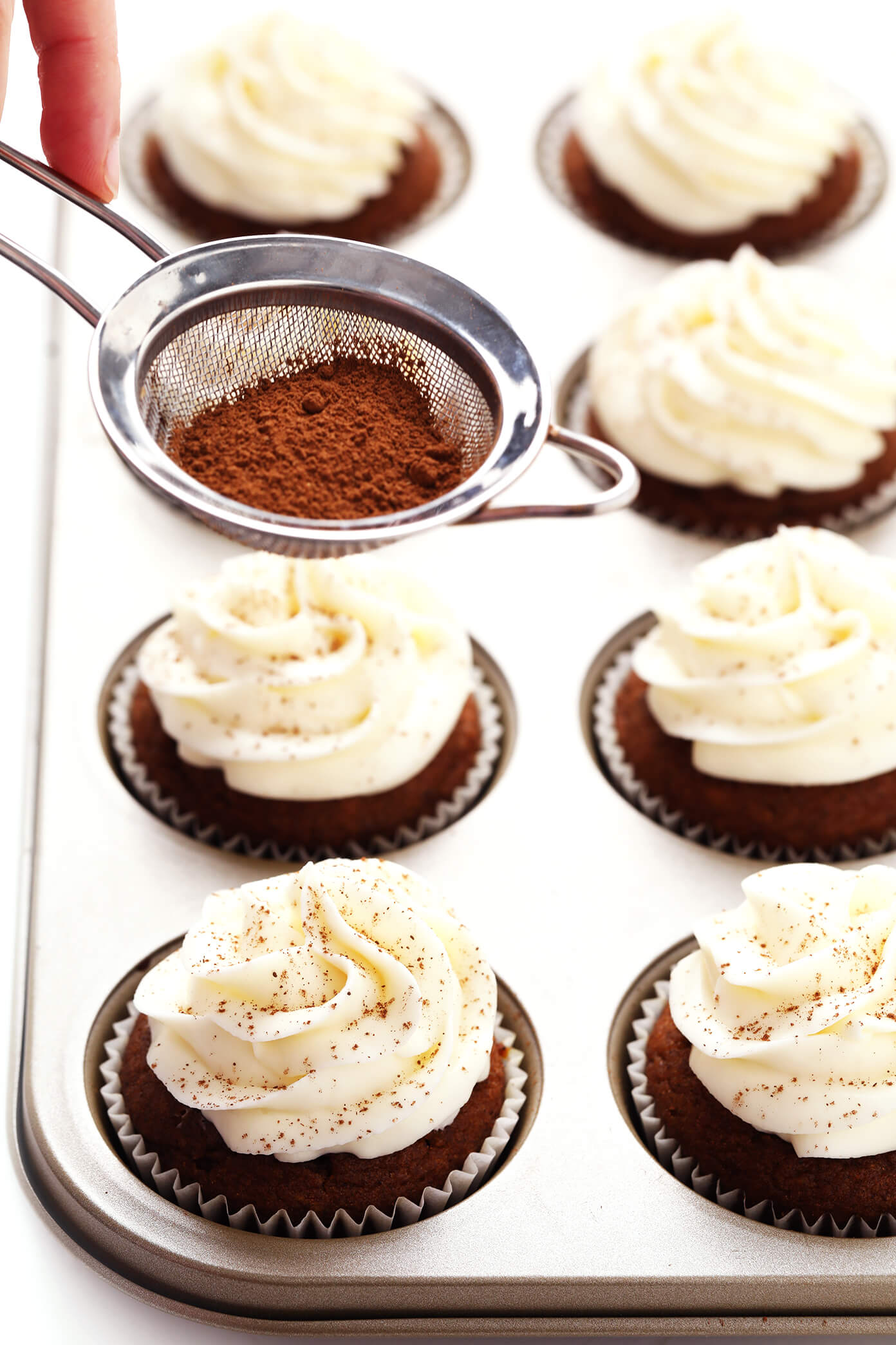 Sprinkling Cinnamon on Pumpkin Cupcakes