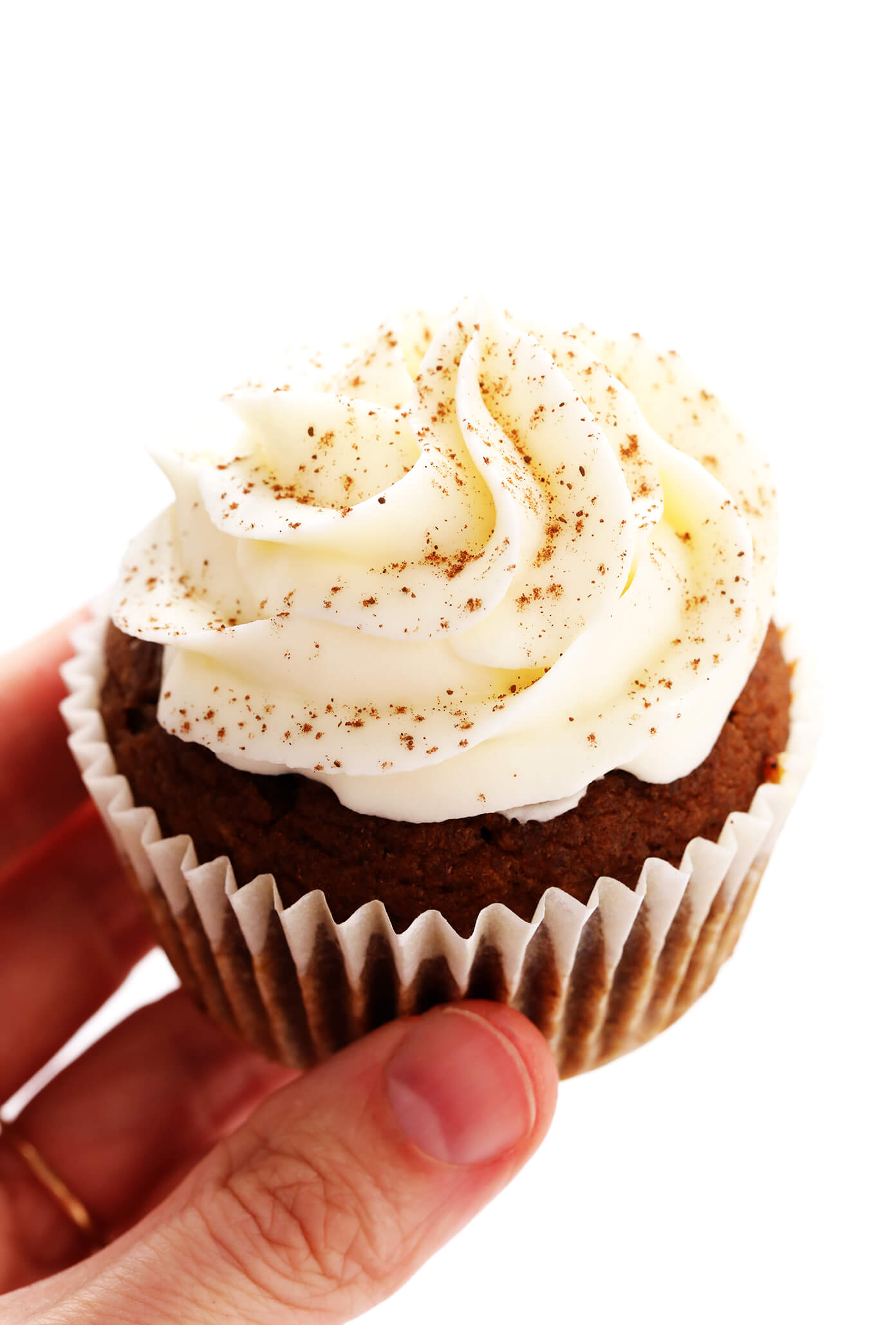 Segurando um cupcake de abóbora com cobertura de cream cheese