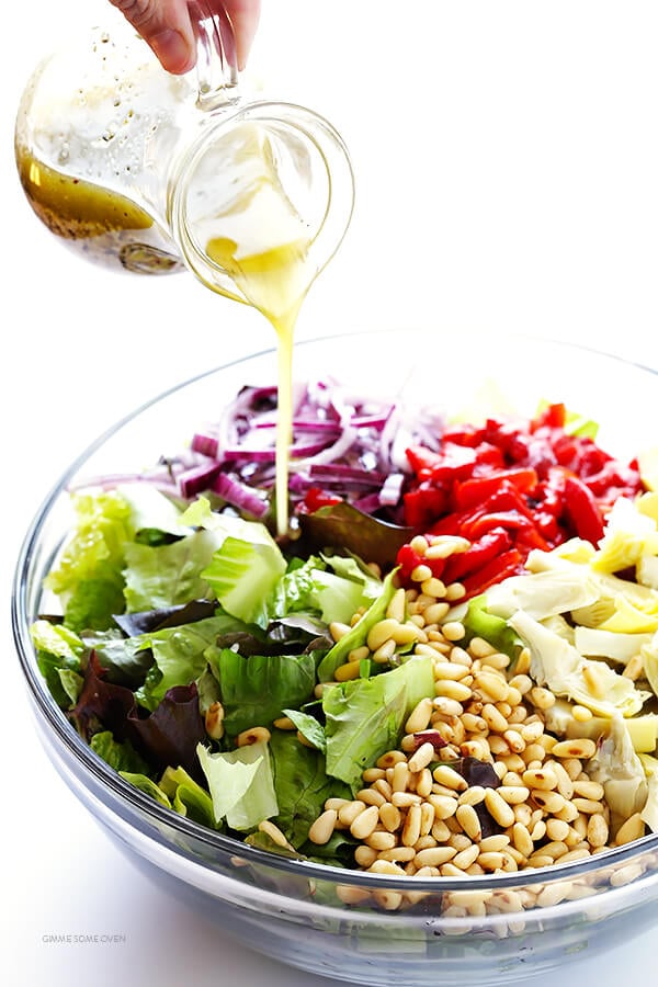 Our Family's Favorite Salad is made with lots of artichoke hearts, roasted red peppers, toasted pine nuts, and a zesty Parmesan vinaigrette. SO delicious, and always a crowd pleaser! | gimmesomeoven.com