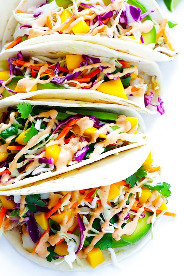 This Mango Chipotle Fish Tacos recipe is made with flaky mild fish, filled with a zesty mango slaw, and drizzled with a creamy chipotle lime sauce. So easy to make, and ready to go in less than 30 minutes! | gimmesomeoven.com