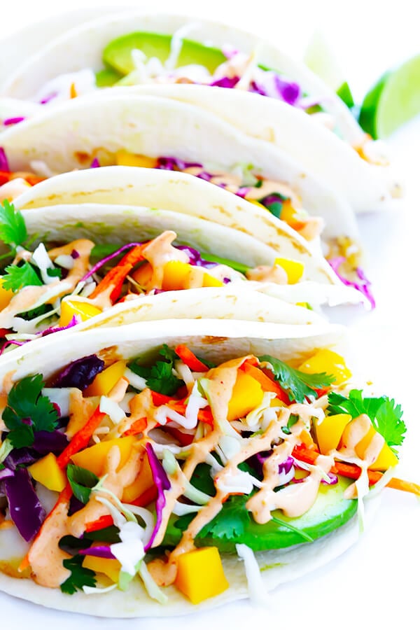 This Mango Chipotle Fish Tacos recipe is made with flaky mild fish, filled with a zesty mango slaw, and drizzled with a creamy chipotle lime sauce. So easy to make, and ready to go in less than 30 minutes! | gimmesomeoven.com