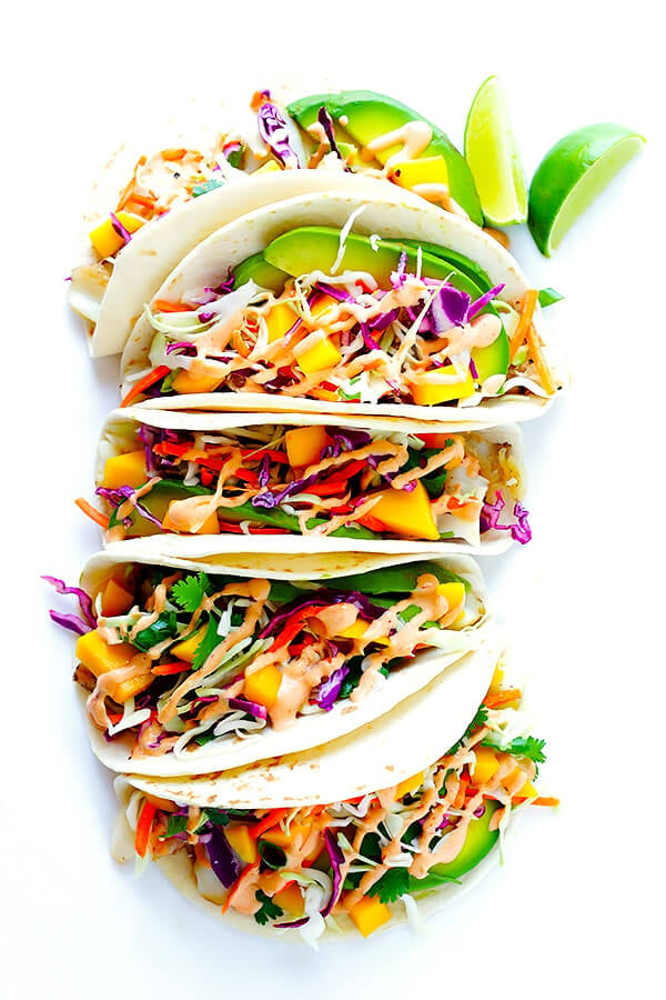 This Mango Chipotle Fish Tacos recipe is made with flaky mild fish, filled with a zesty mango slaw, and drizzled with a creamy chipotle lime sauce. So easy to make, and ready to go in less than 30 minutes! | gimmesomeoven.com