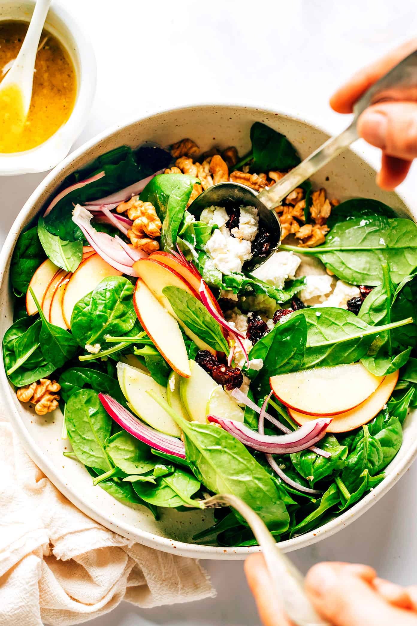 Tossing Apple Spinach Salad in a mixing bowl