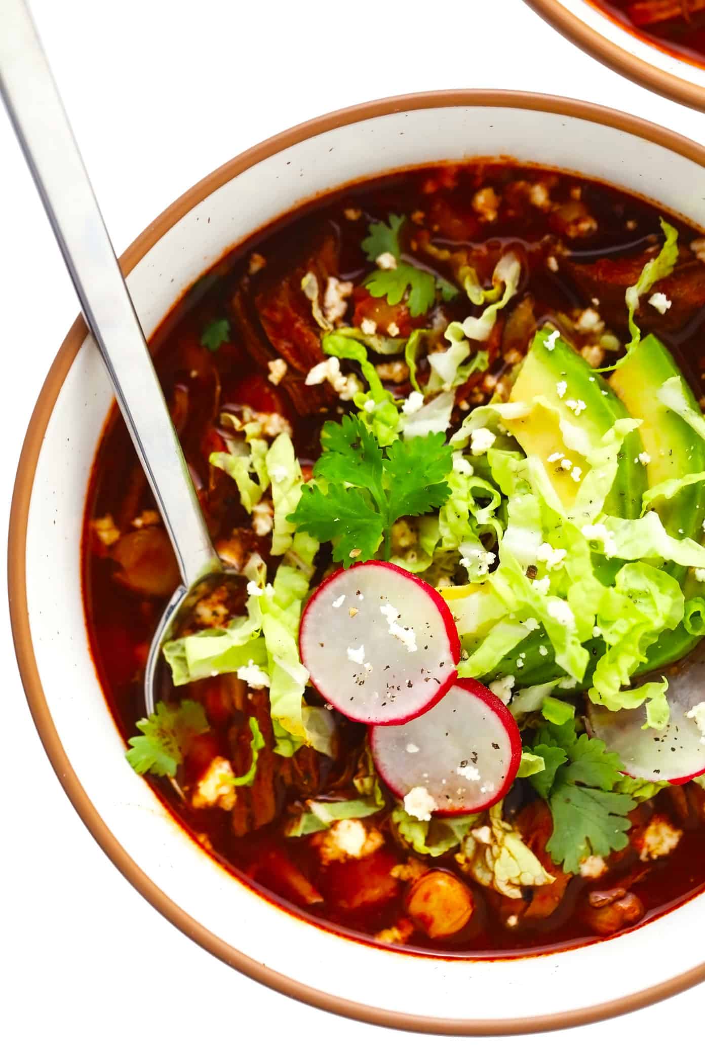 Bowl of pork pozole with avocado, radishes, cilantro and cabbage