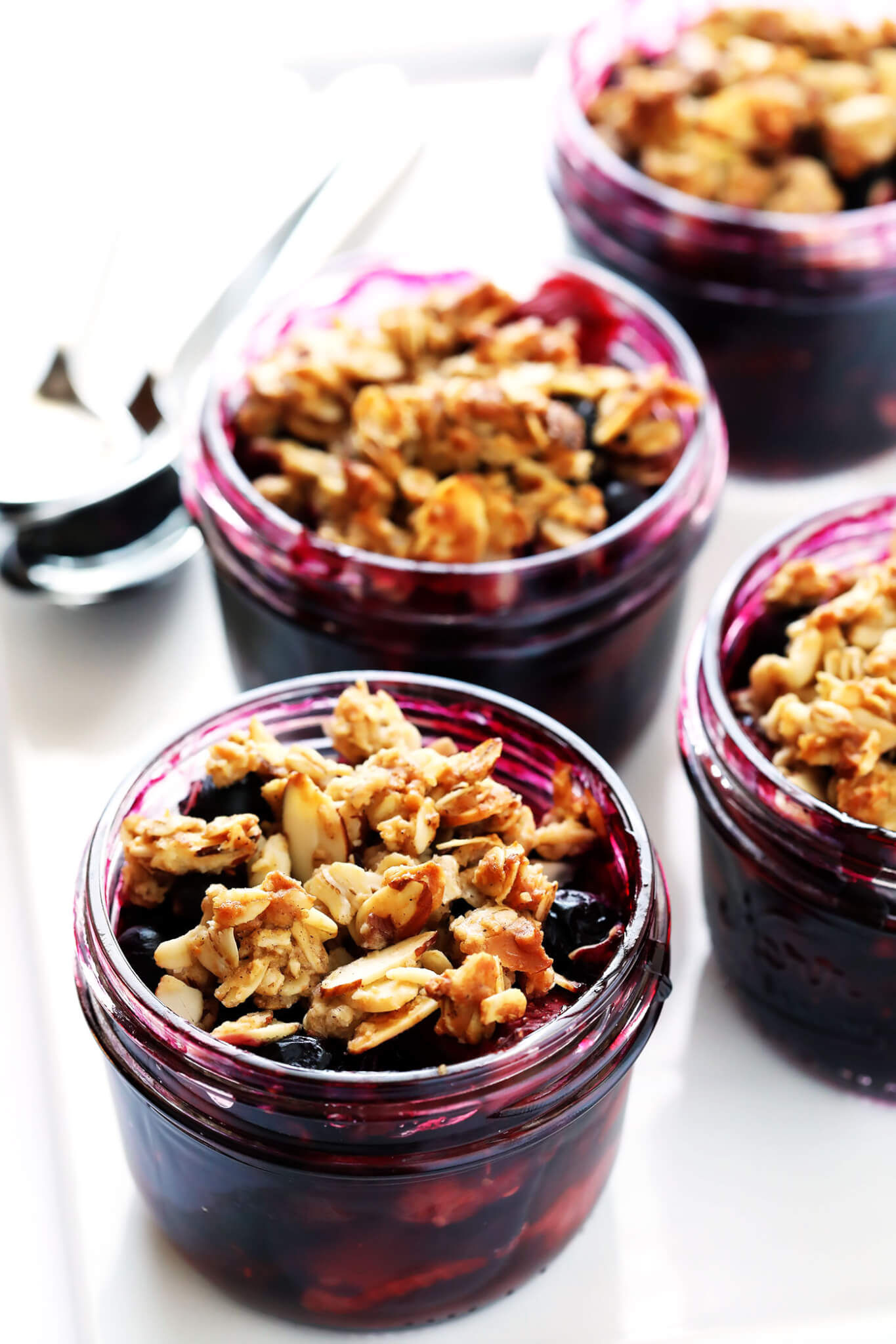 These Mini Mason Jar Fruit Crisps are easy to make with blueberries or your favorite fruit, and topped with a yummy oatmeal-almond topping. They're the perfect quick and easy and seasonal dessert! | gimmesomeoven.com