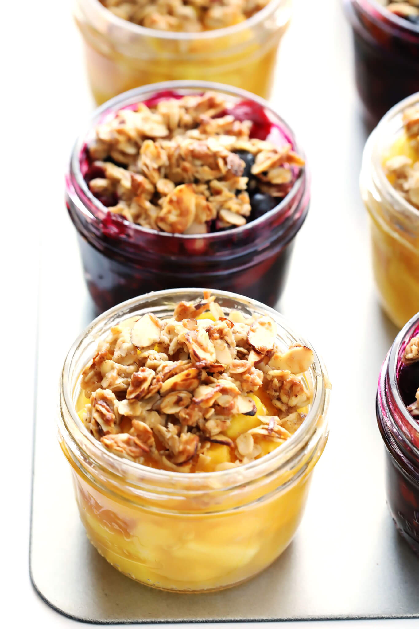 This Mini Mason Jar Fruit Crisps recipe can be made with your favorite seasonal fruit, they're topped with a delicious oatmeal-almond crumble, and they are SO delicious! Feel free to make them with blueberries, strawberries, cherries, peaches, pineapple, apples, pears...you name it! They're one of my favorite easy dessert recipes. | gimmesomeoven.com (Gluten-Free / Vegetarian)