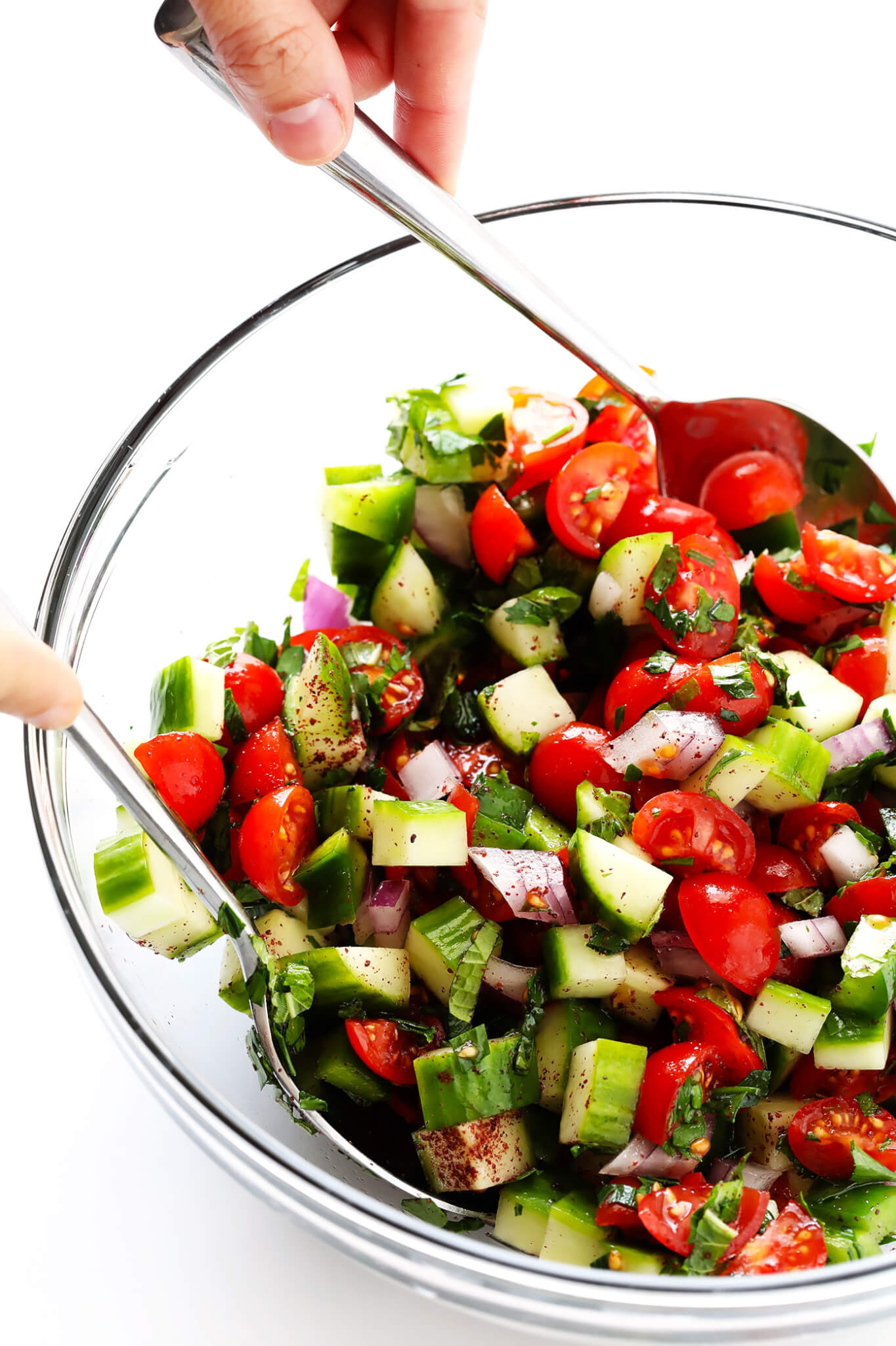 This delicious Israeli Salad recipe is quick and easy to make, full of the fresh flavors of tomatoes, cucumbers, peppers, mint, parsley and sumac, and it's so delicious! Serve it up on its own, or use it to make a simple pita wrap or hummus dip! | gimmesomeoven.com
