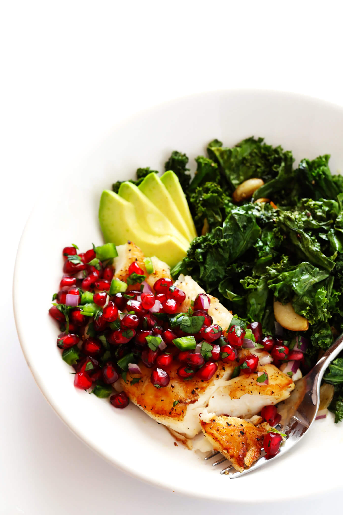 This 20-Minute Pan-Seared Fish is topped with a sweet pomegranate salsa, and serve up with fresh avocado and garlicky kale. It's an quick and easy dinner recipe that you can make with your favorite fish (halibut, cod, salmon, tilapia, etc.) that's also naturally gluten-free, and SO delicious!