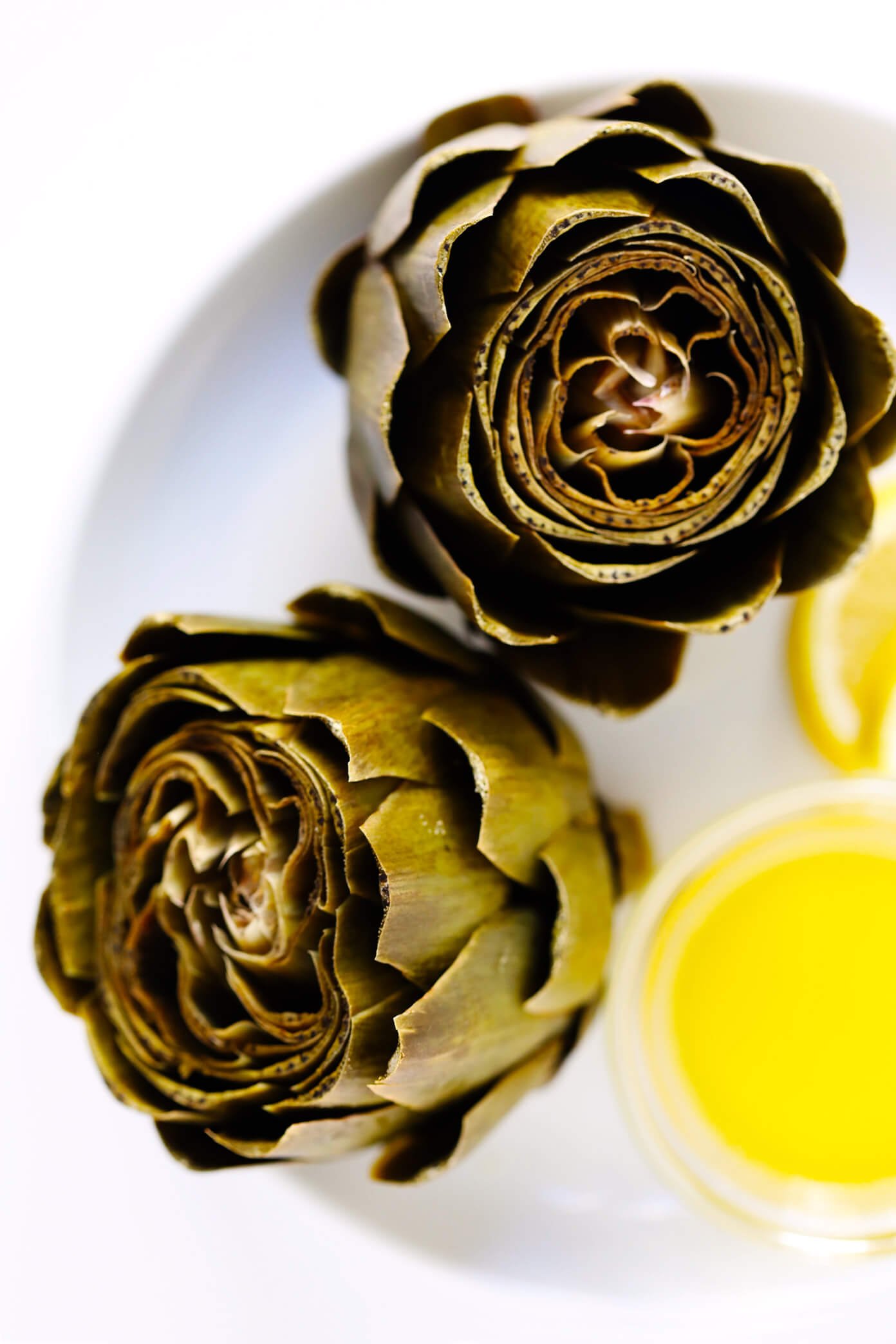 LOVE this Instant Pot Steamed Artichokes recipe! It's extra quick and easy when made in the pressure cooker, and made with a subtle garlic lemon seasoning (plus a buttery dipping sauce, if you'd like) that makes this the perfect side dish. | Gimme Some Oven (Vegetarian / Vegan / Gluten-Free)