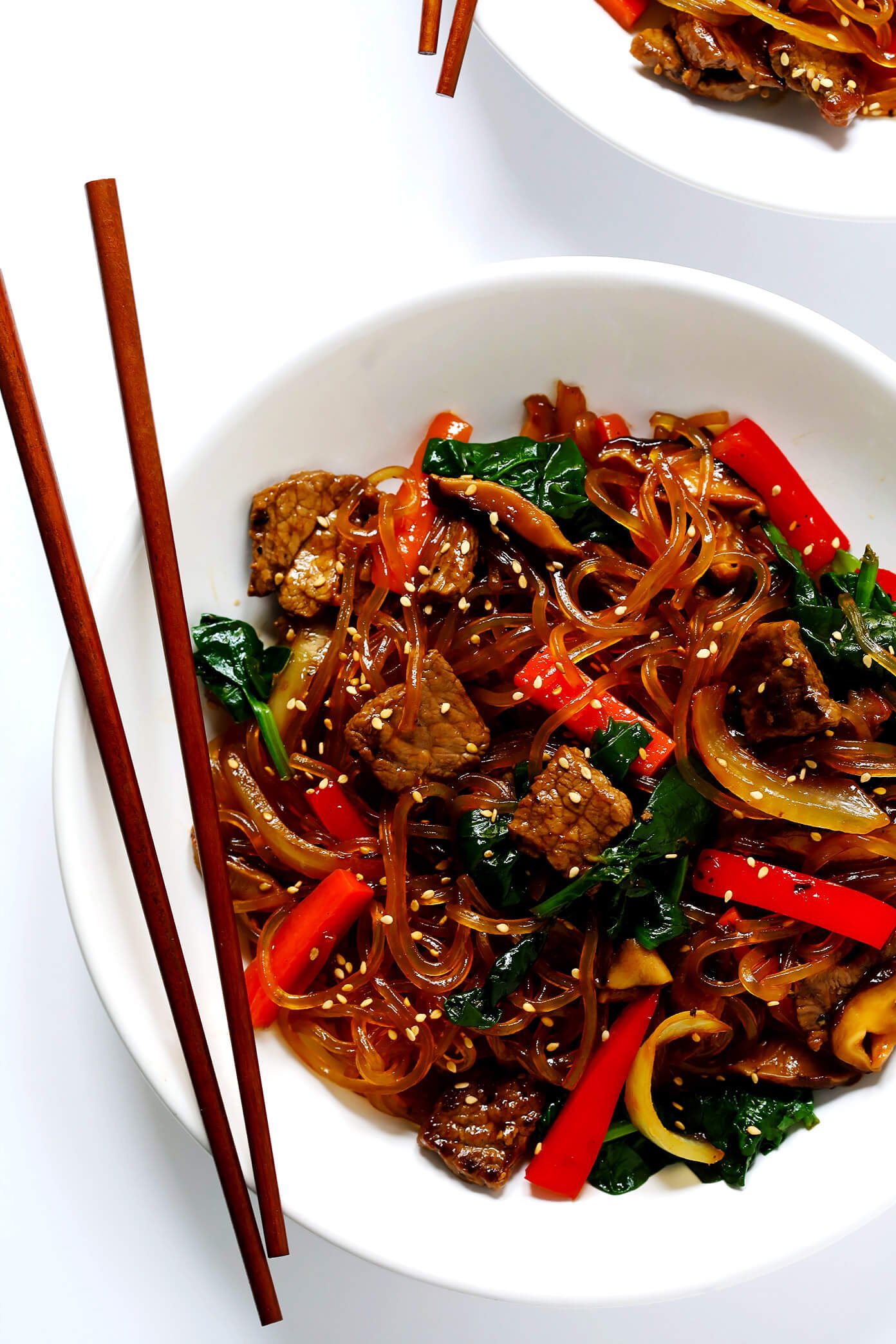Japchae, this easy Korean noodle stir-fry recipe, is quick and easy to make, it's full of veggies (red peppers, carrots, onions, mushrooms, spinach), and tossed in the most delicious sesame-soy-maple sauce. Feel free to make yours with steak, chicken, pork, shrimp, or tofu. Or just keep it vegan with veggies only. | Gimme Some Oven #stirfry #korean #japchae #dinnerrecipes #glutenfree http://www.beincooking.com/