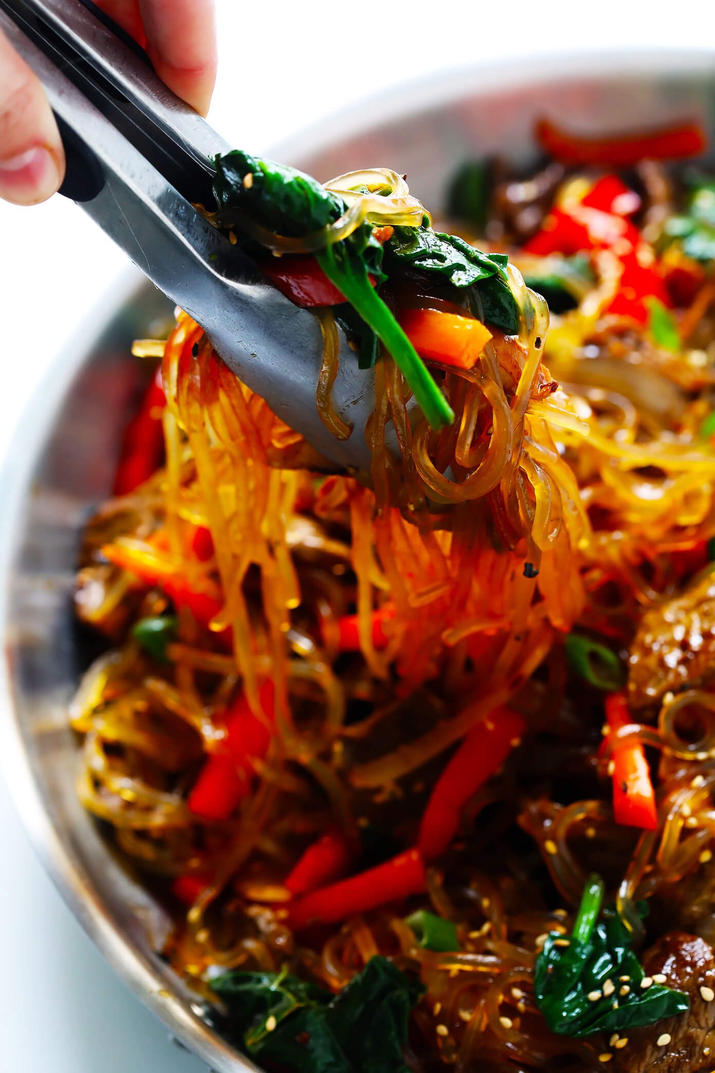 Japchae, this easy Korean noodle stir-fry recipe, is quick and easy to make, it's full of veggies (red peppers, carrots, onions, mushrooms, spinach), and tossed in the most delicious sesame-soy-maple sauce. Feel free to make yours with steak, chicken, pork, shrimp, or tofu. Or just keep it vegan with veggies only. | Gimme Some Oven #stirfry #korean #japchae #dinnerrecipes #glutenfree http://www.beincooking.com/