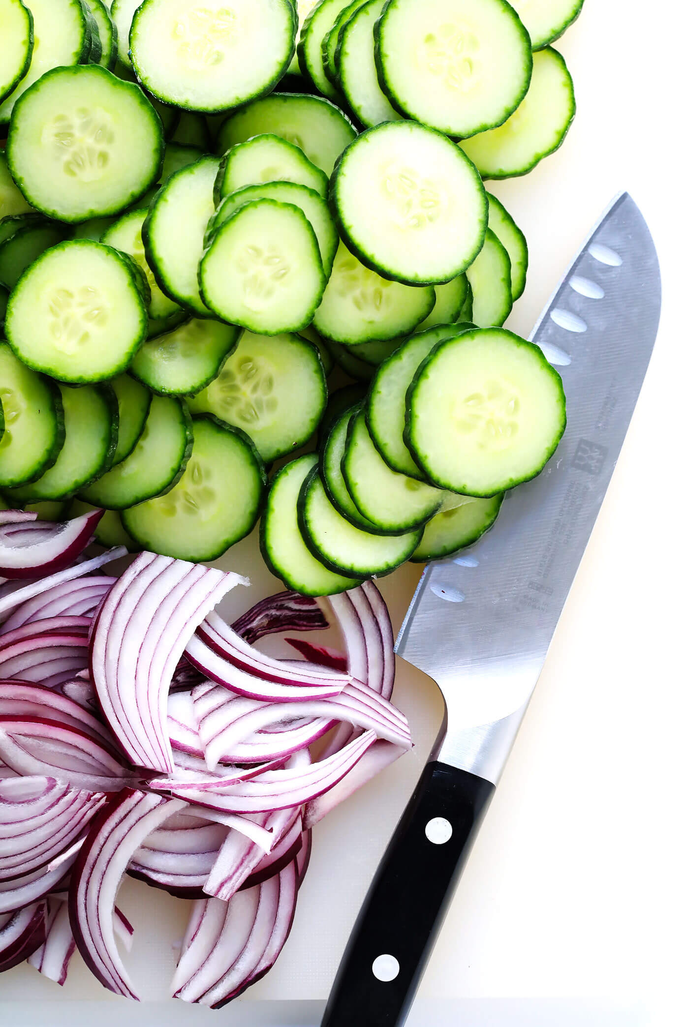 Cortando pepino inglês e cebola roxa para fazer uma salada de acompanhamento