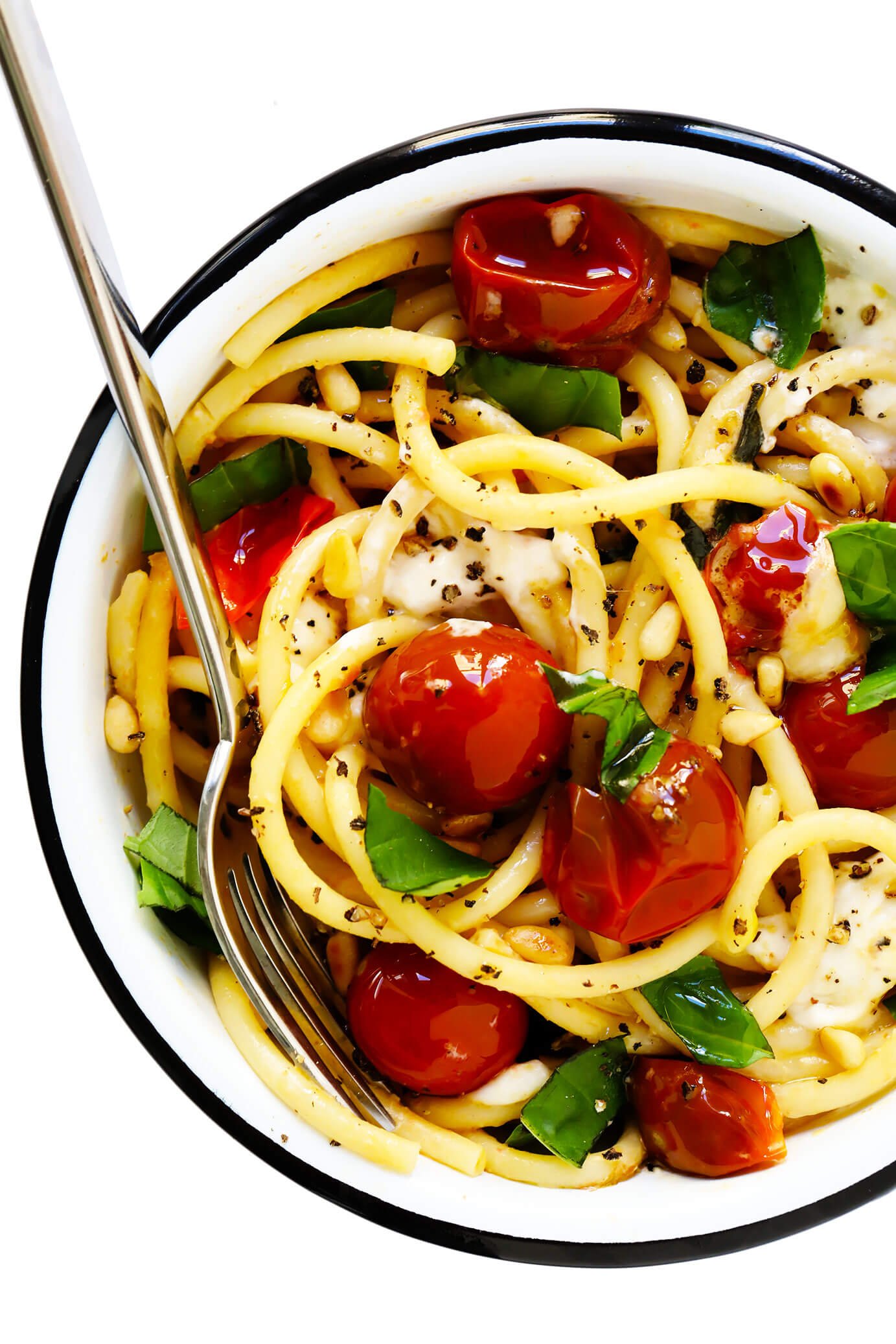 Serving bowl of pasta with cherry tomatoes, burrata and basil