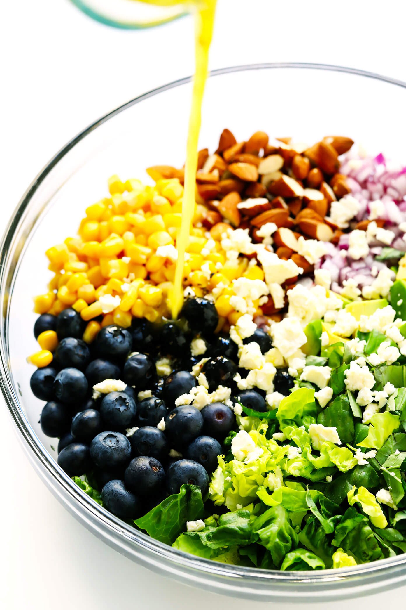 Drizzling lemon dressing into blueberry salad