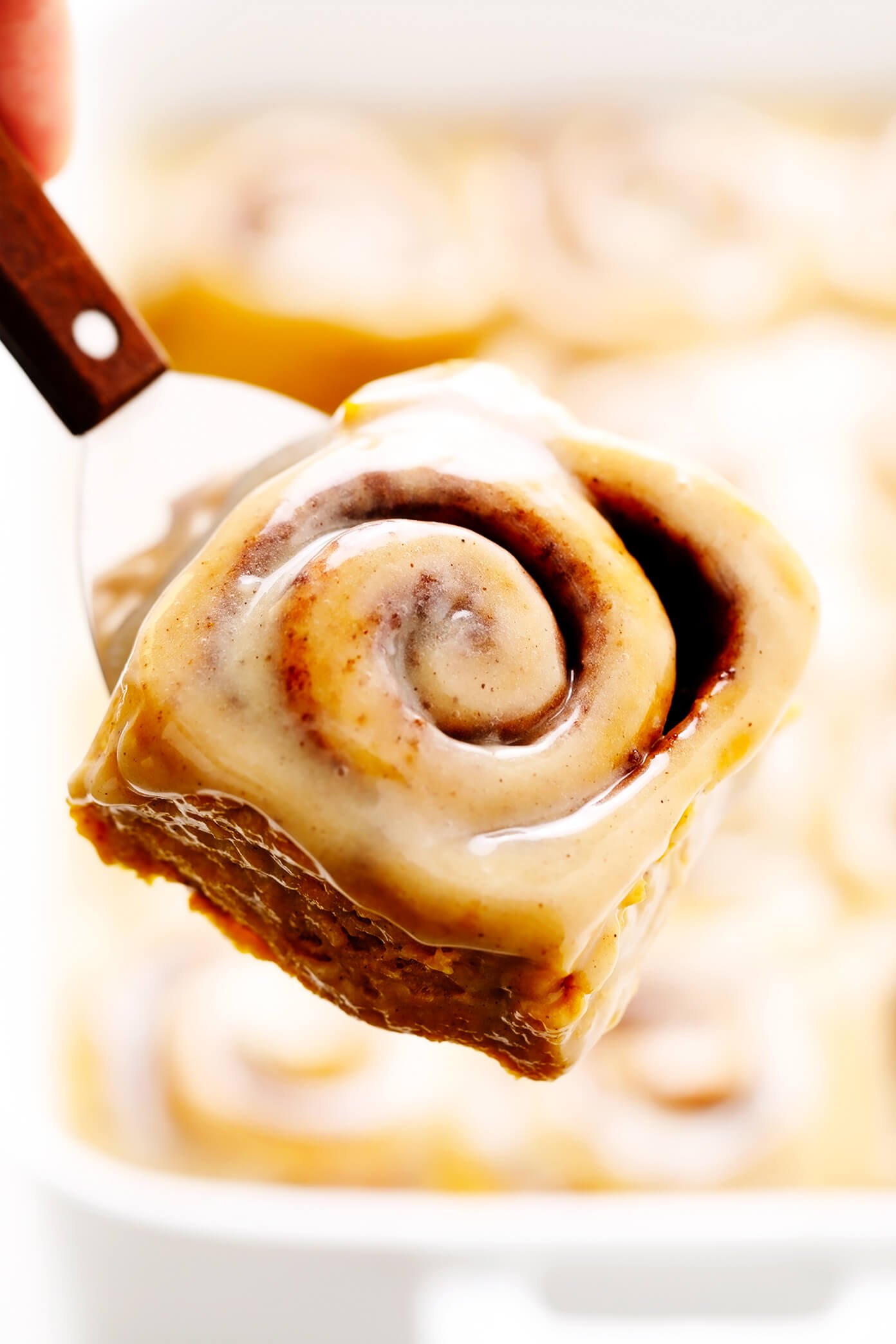 Pumpkin Cinnamon Rolls lifting out of pan