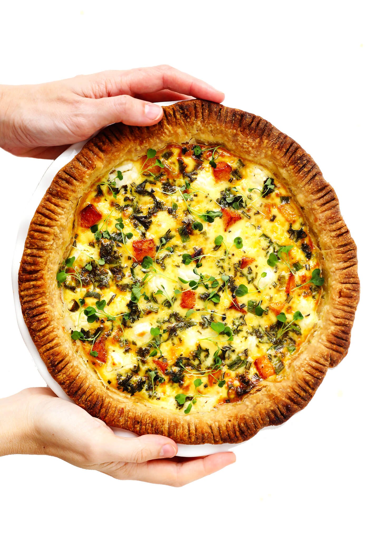 Holding a whole pan of Butternut Squash, Kale and Goat Cheese Quiche