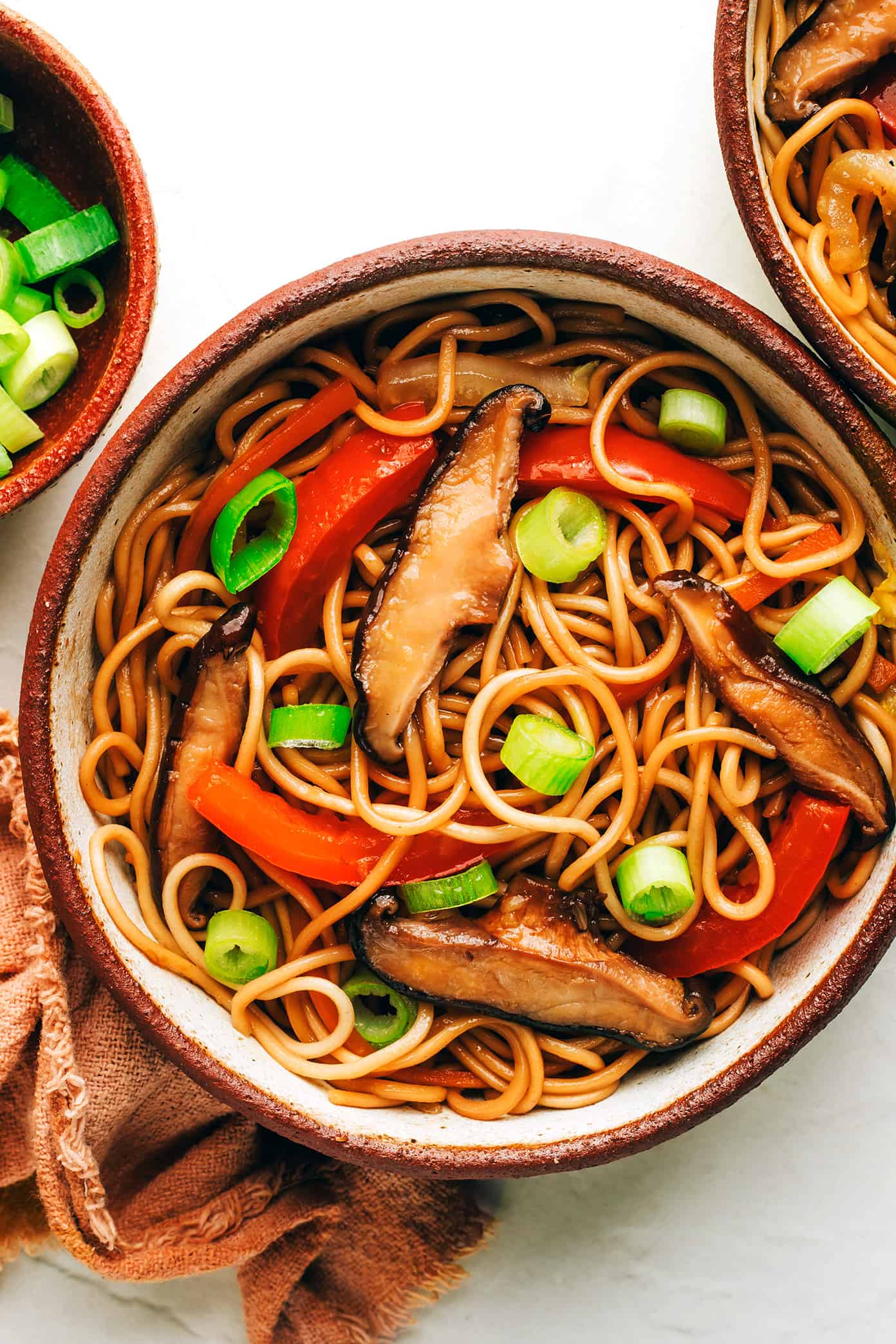 Bowl of chow mein with mushrooms, red peppers and green onions