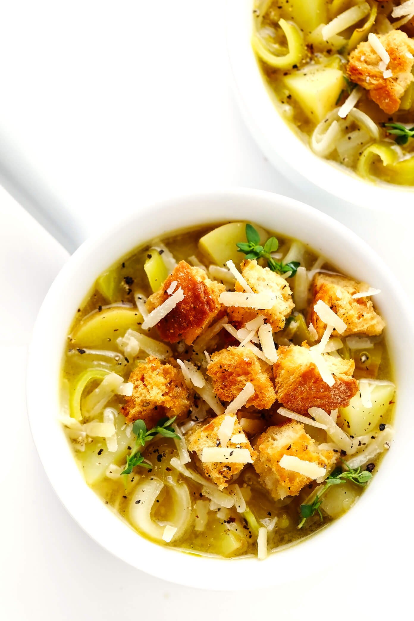 Tigelas de sopa rústica de batata e alho-poró com croutons caseiros e parmesão