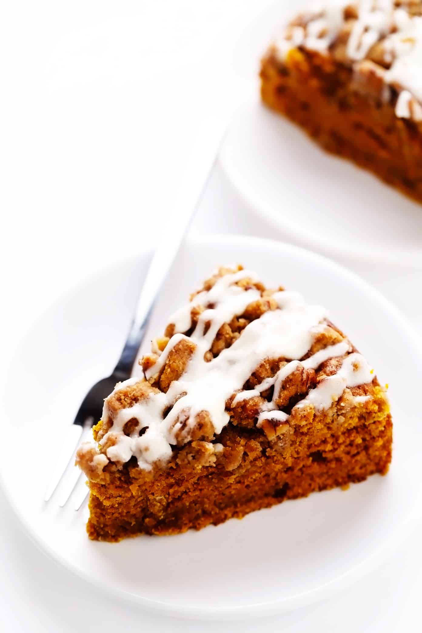 Serving pieces of pumpkin coffee cake with streusel and cream cheese icing
