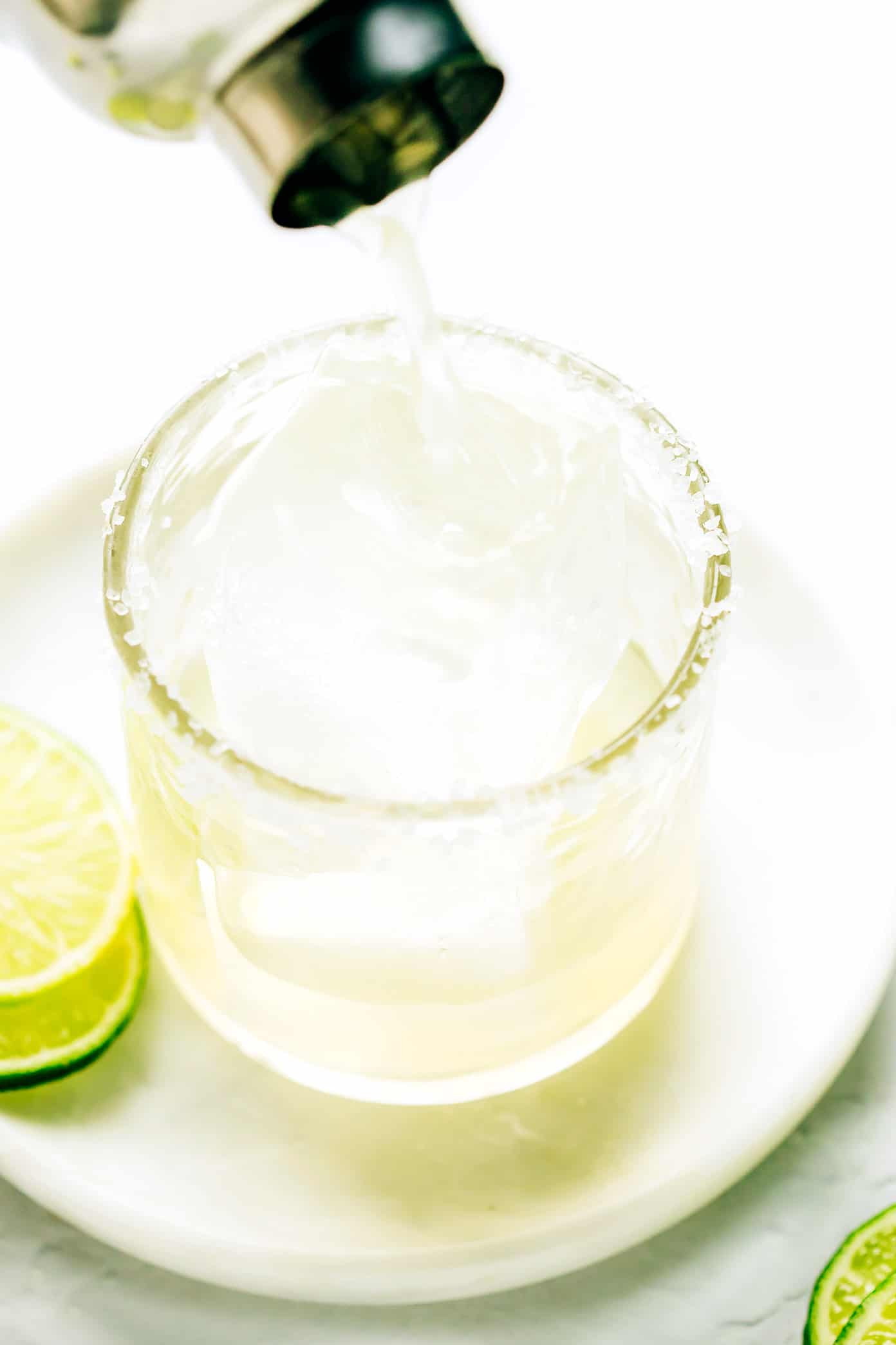 Pouring a bourbon margarita into a salt-rimmed glass