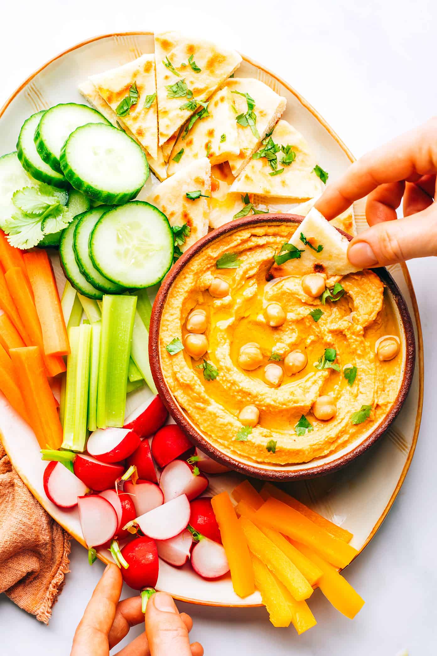 Hummus ao curry vermelho tailandês em uma bandeja com crudités e Naan