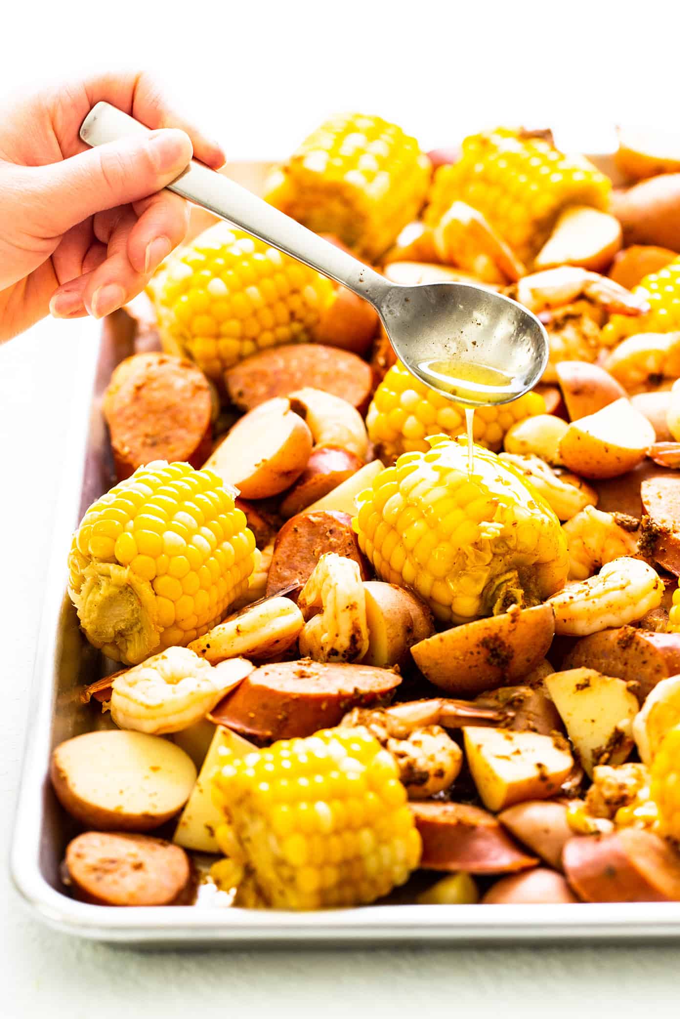 Drizzling brown butter sauce on shrimp boil