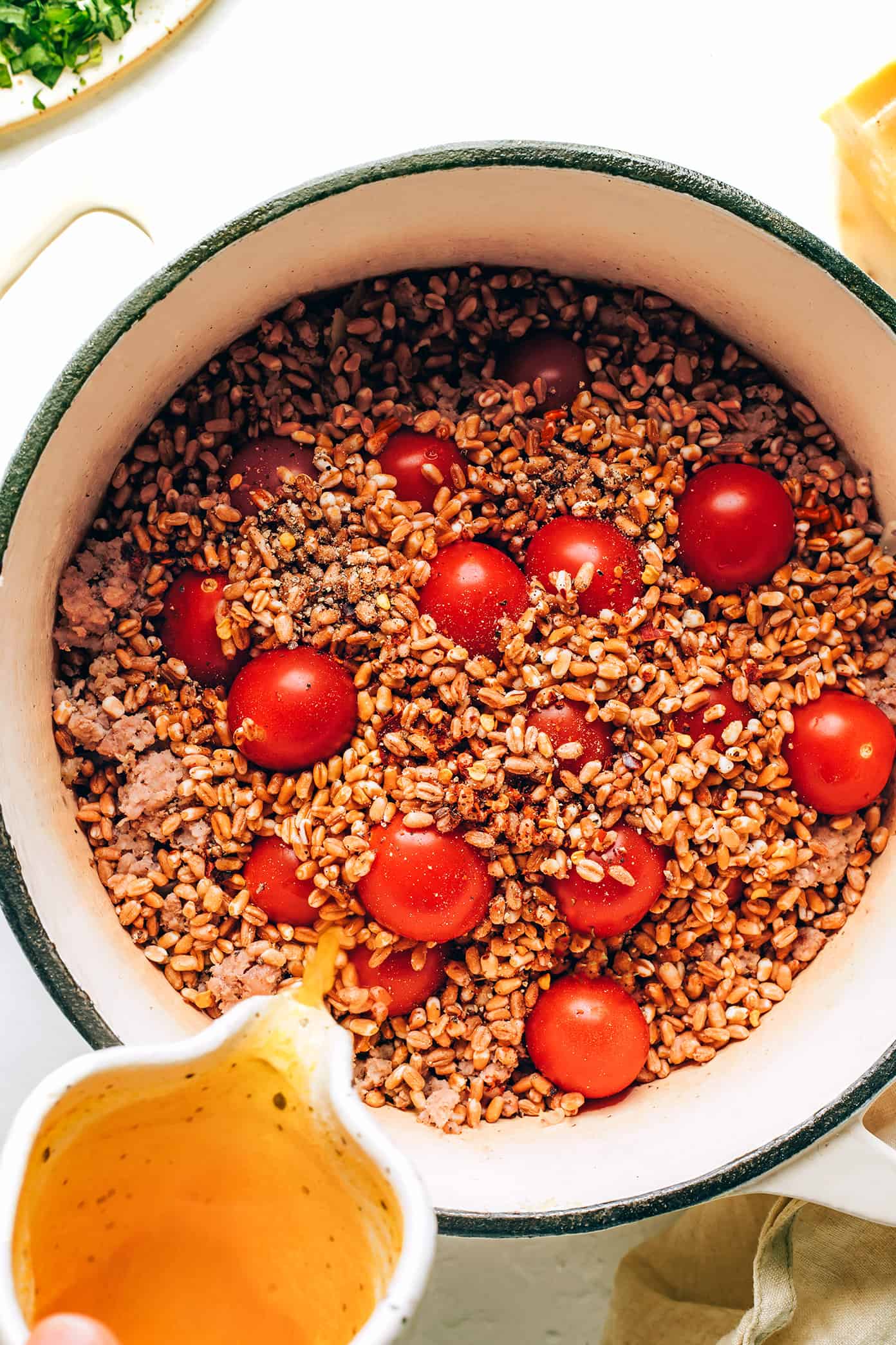 Adding broth to one pot farro with Italian sausage and tomatoes