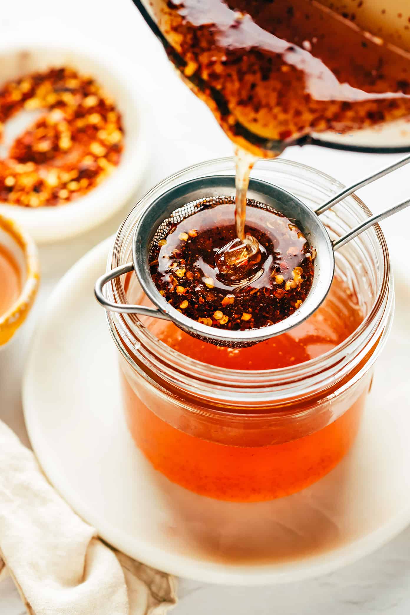 Straining hot honey into jar