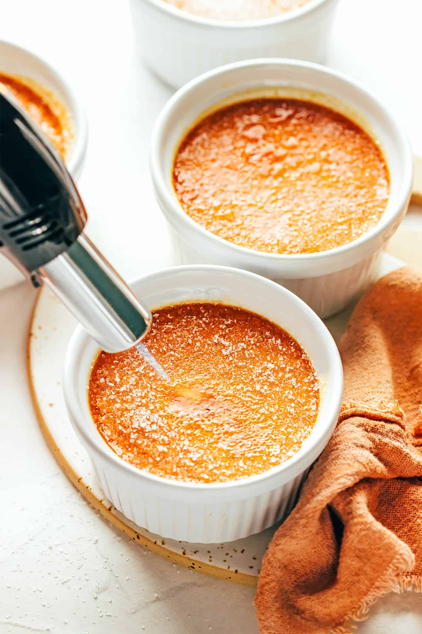 Using a kitchen torch to caramelize the sugar for Crème Brûlée