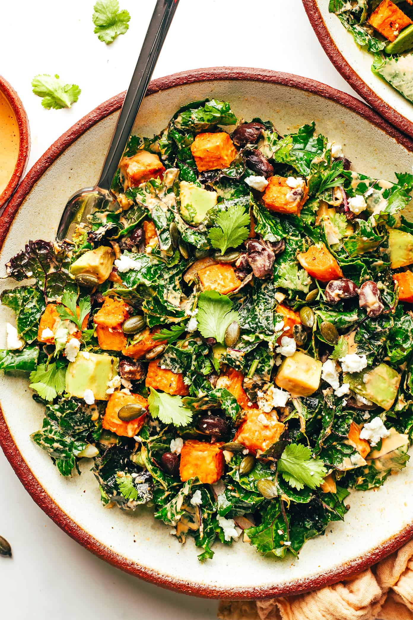 Roasted sweet potato avocado kale salad in bowl with fork