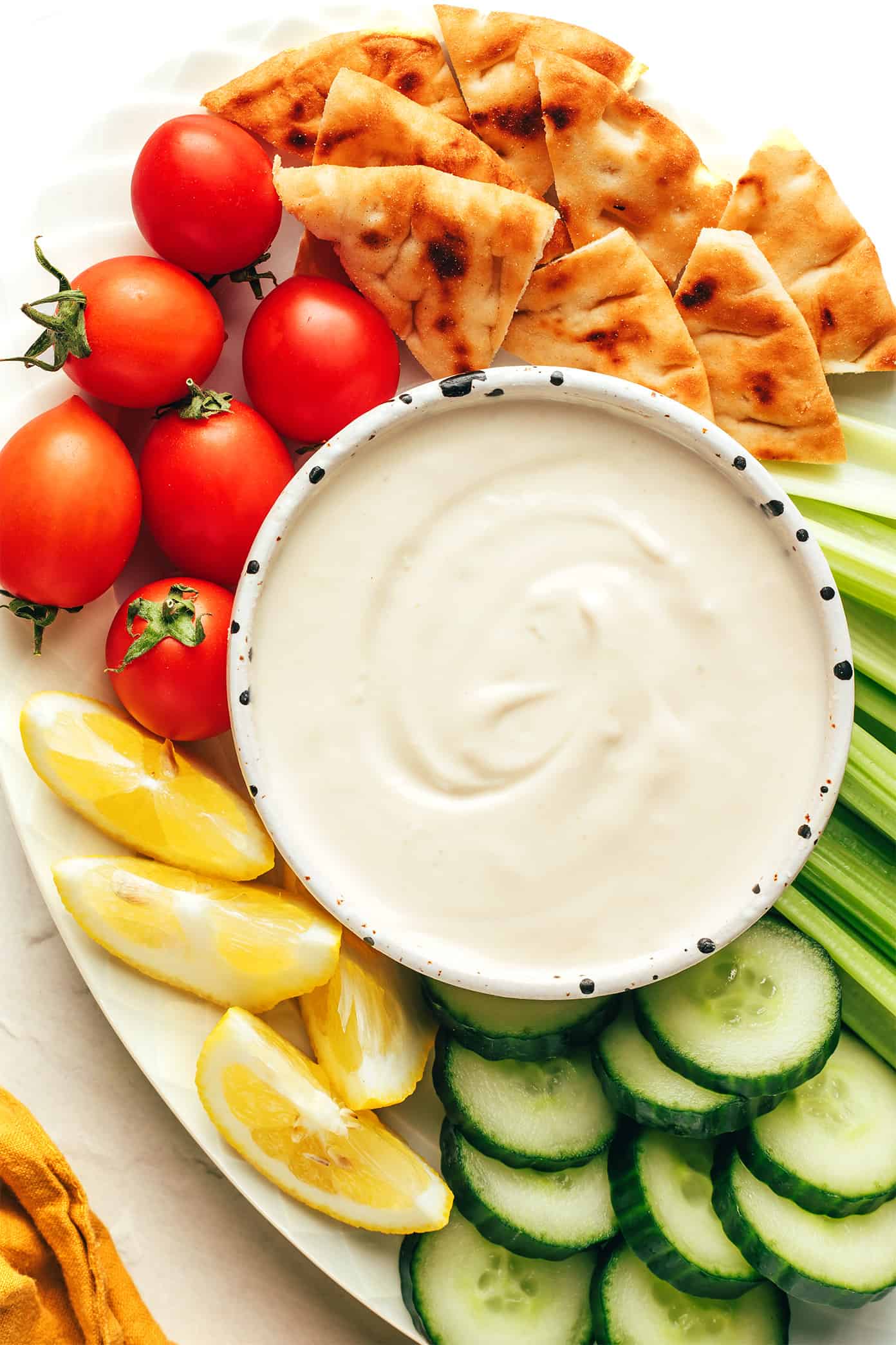 Tahini sauce in bowl with veggies and pita for dipping