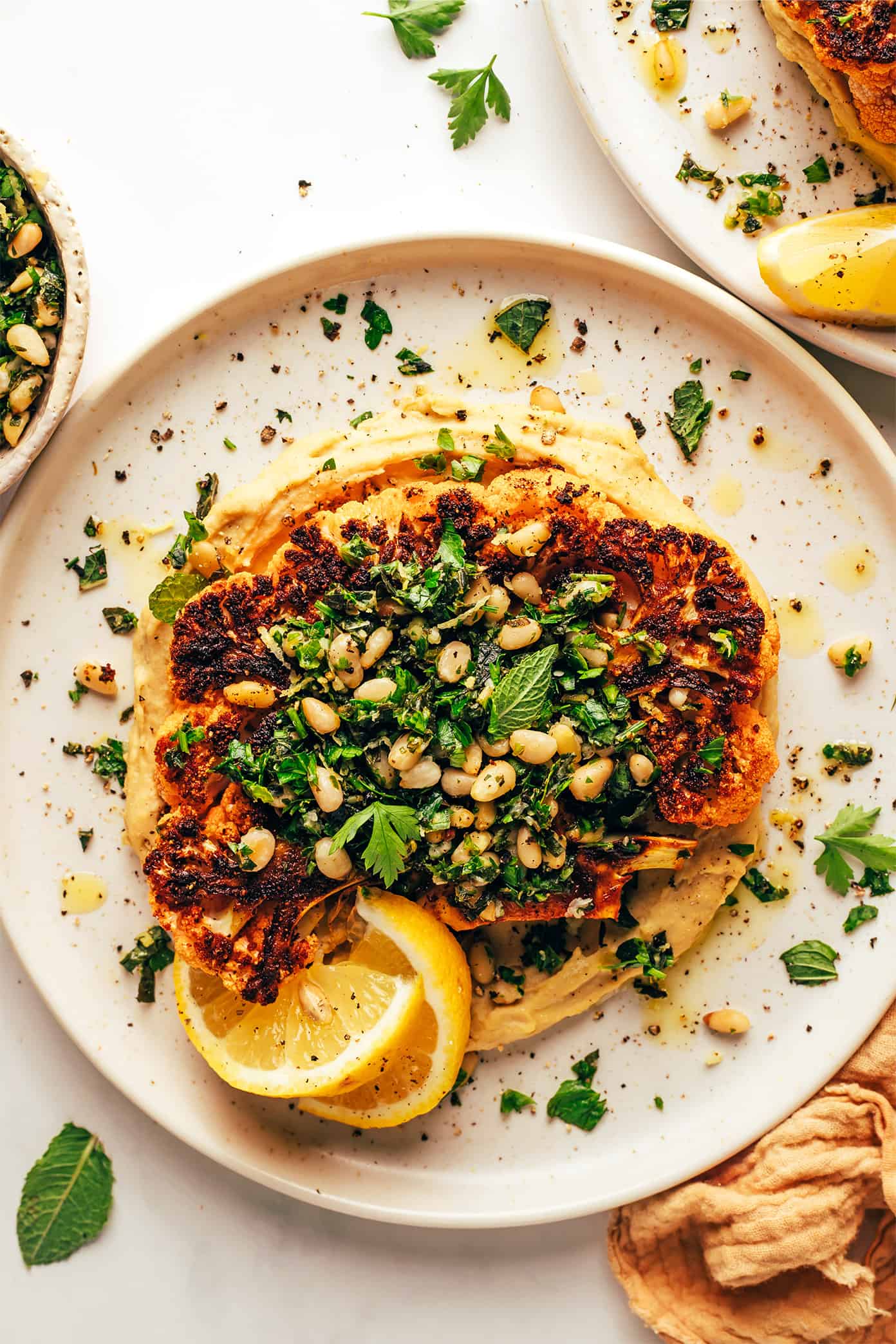 Cauliflower Steaks with Hummus and Gremolata on Serving Plates