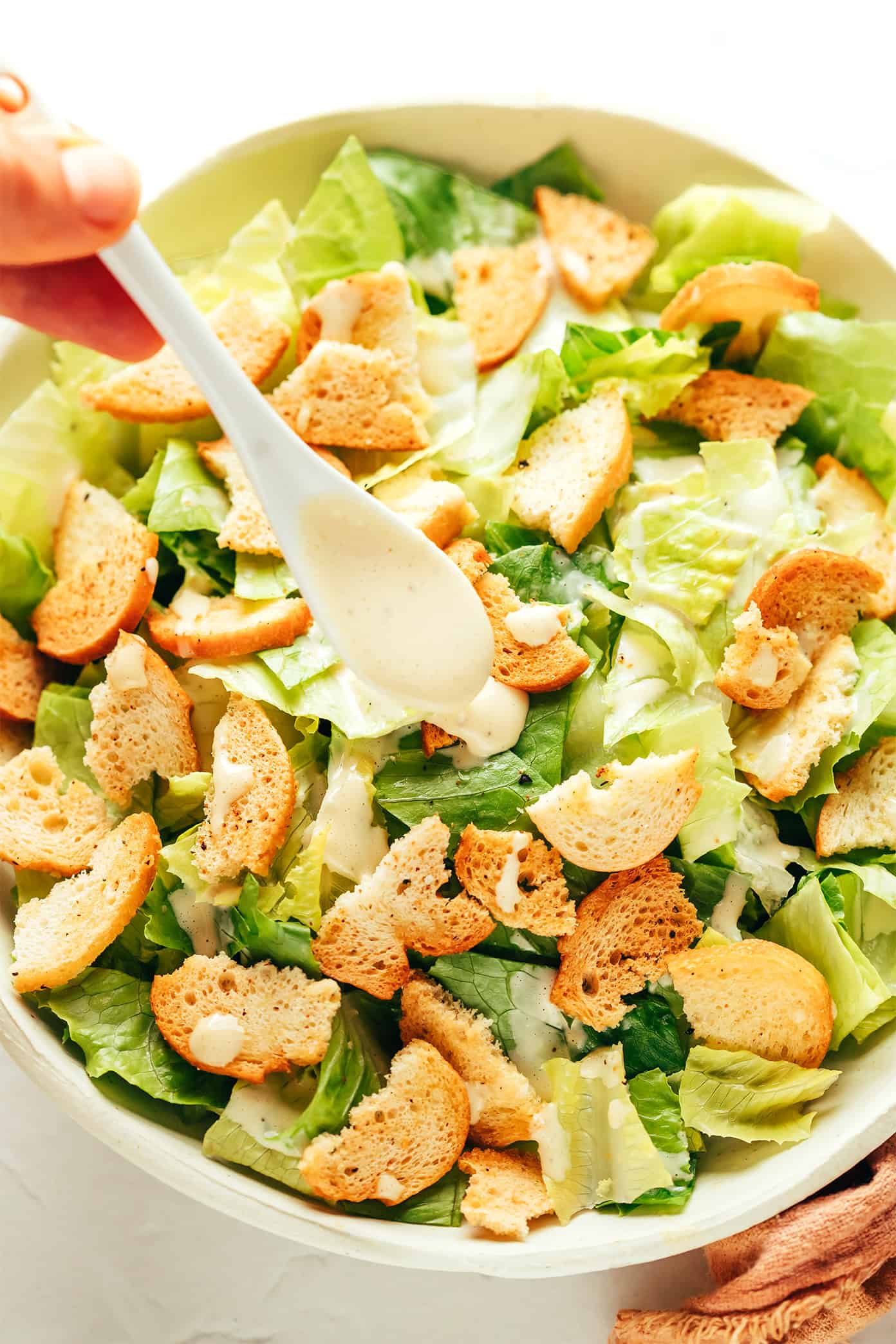 Adding Caesar dressing to salad