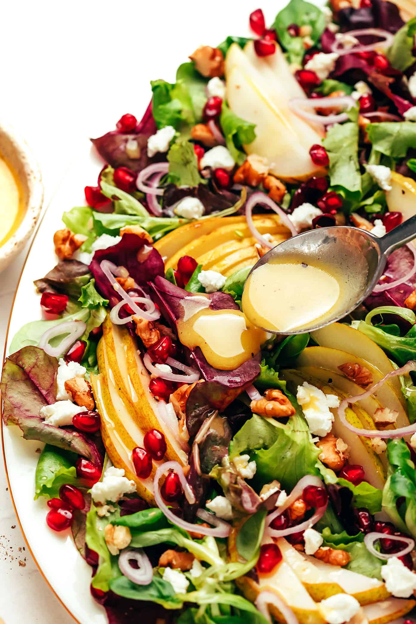 drizzling white balsamic vinaigrette on pear salad